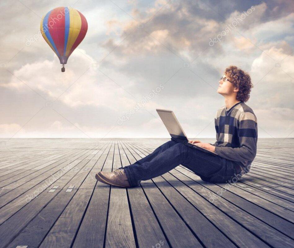 Foto chico escribiendo en un ordenador. Al fondo un globo