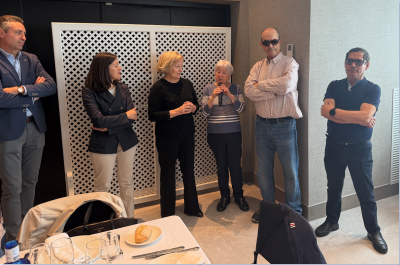 grupo de personas donde una sostiene el micrófono para hablar en una comida 