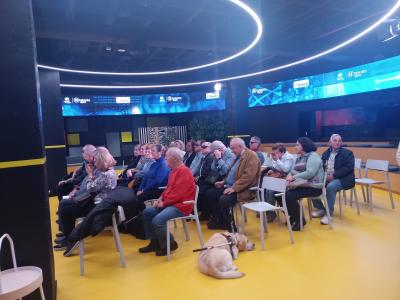 ASISTENTES SUPO MADRID AL EVENTO DEL HUB DE POR TALENTO DIGITAL. SE VE UN GRUPO GRANDE DE PERSONAS EN UNA SALA REDONDA REPLETA DE PANTALLAS Y RECURSOS TECNOLÓGICOS.