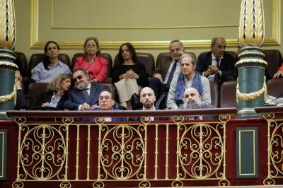 Varias personas asisten sentadas en la tribuna de un salón institucional con barandilla ornamentada.