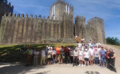 Grupo de participantes de la excursión de SUPO Vigo-Pontevedra posando frente a una fortaleza medieval durante su visita al norte de Portugal.