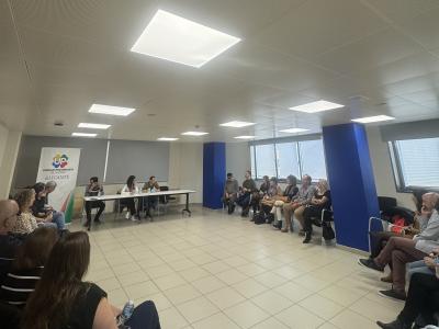 Se muestra un sillas formando un semicírculo con los miembros de la ejecutiva y los moderadores en una mesa