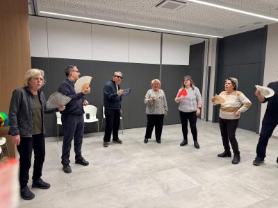 Fotografia en la que aparecen varios participantes, durante el taller de risoterapia en la agencia de la Once en Girona. llevan en la mano un abanico.