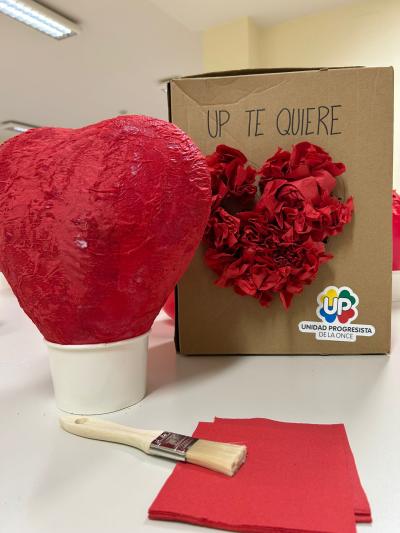 Globo con forma de corazón , cubierto cuidadosamente con capas de servilletas rojas pegadas con cola, formando una superficie firme y texturizada que simboliza el amor y la inclusión.