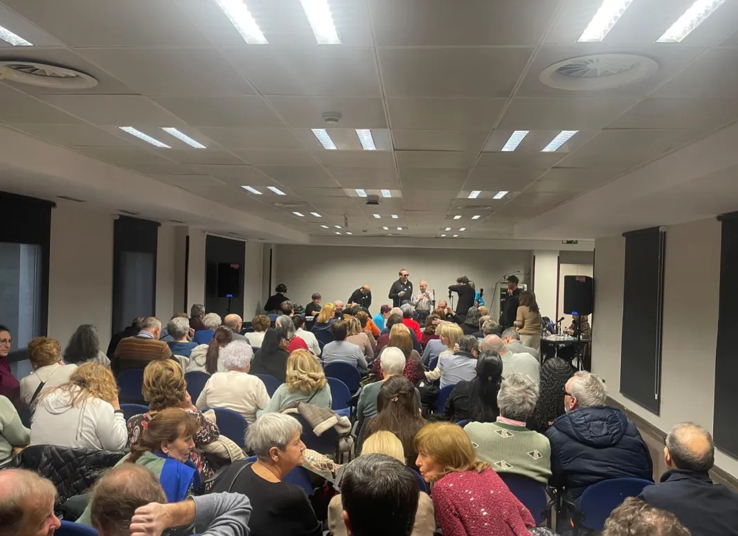 La sala repleta de asistentes y al fondo el concierto. 