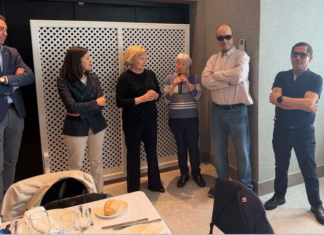 grupo de personas donde una sostiene el micrófono para hablar en una comida 