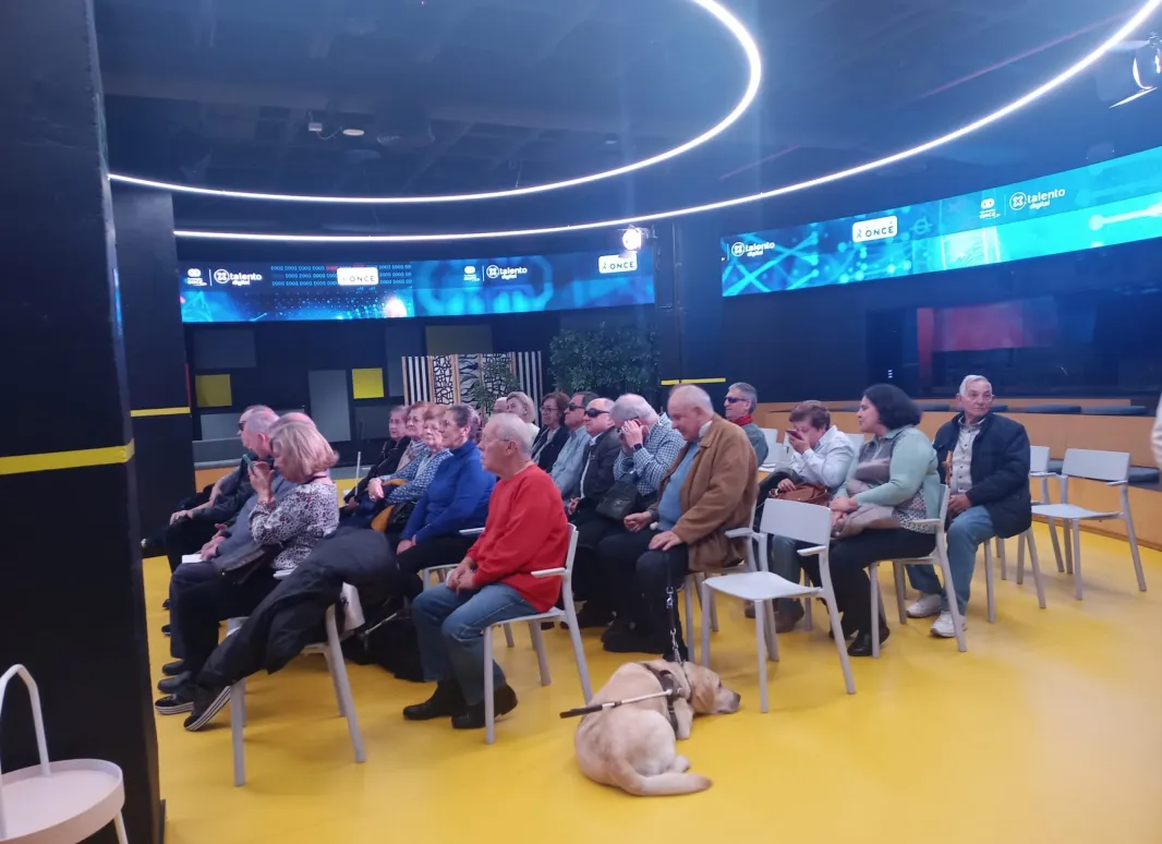 ASISTENTES SUPO MADRID AL EVENTO DEL HUB DE POR TALENTO DIGITAL. SE VE UN GRUPO GRANDE DE PERSONAS EN UNA SALA REDONDA REPLETA DE PANTALLAS Y RECURSOS TECNOLÓGICOS. 