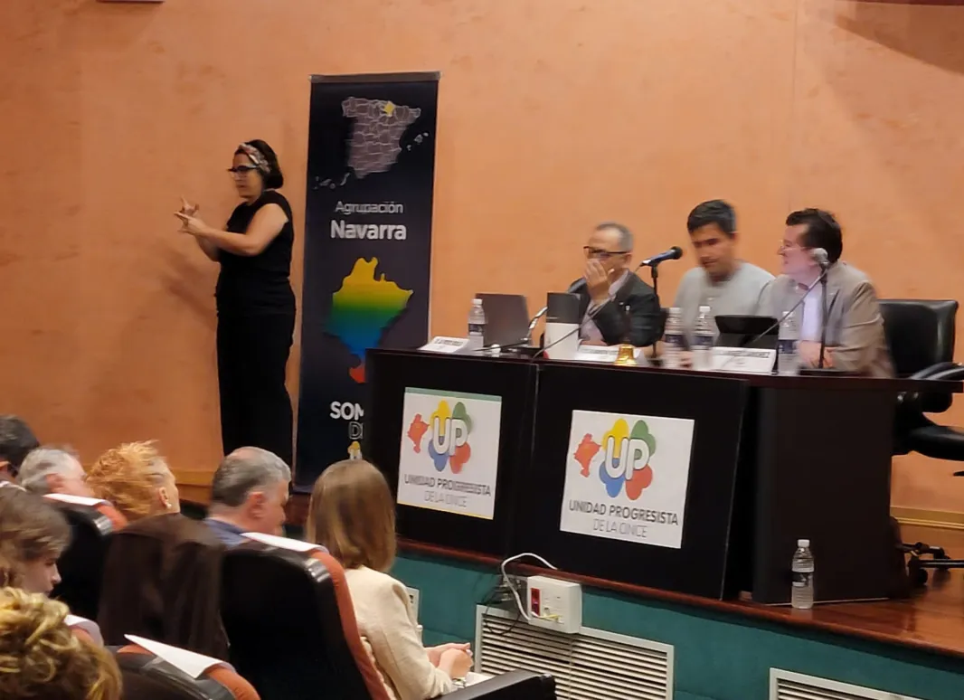 En el salón de actos de la ONCE en la mesa está Ángel Sánchez, Ramón Estévez y Alfredo Borja con la intérprete en lengua de signos al fondo.