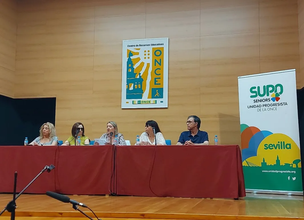 Imagen del escenario donde se desarrolló la Asamblea en la que en el centro se visualiza la mesa con los cinco ponentes quedando a la derecha la enara de SUPO Sevilla