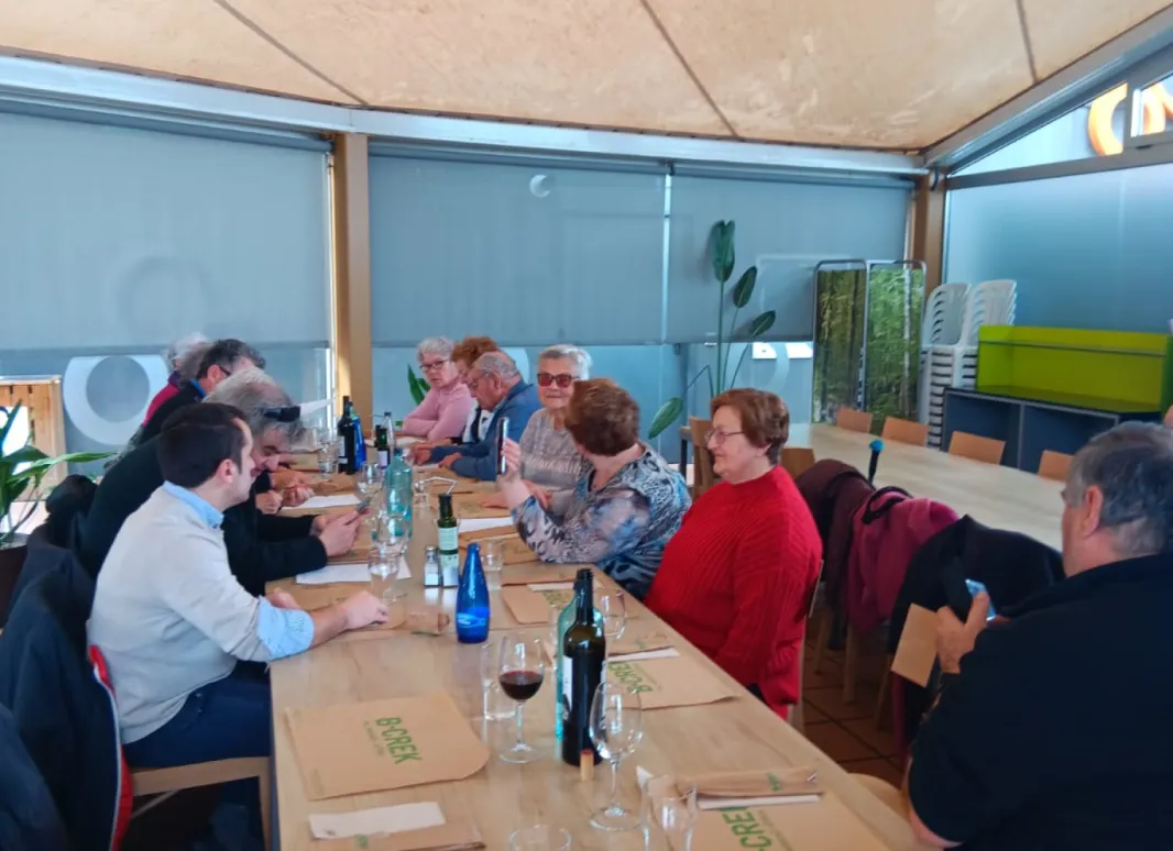 Fotografía en la que se muestra el grupo de asistentes a la comida conversando entre ellos. 