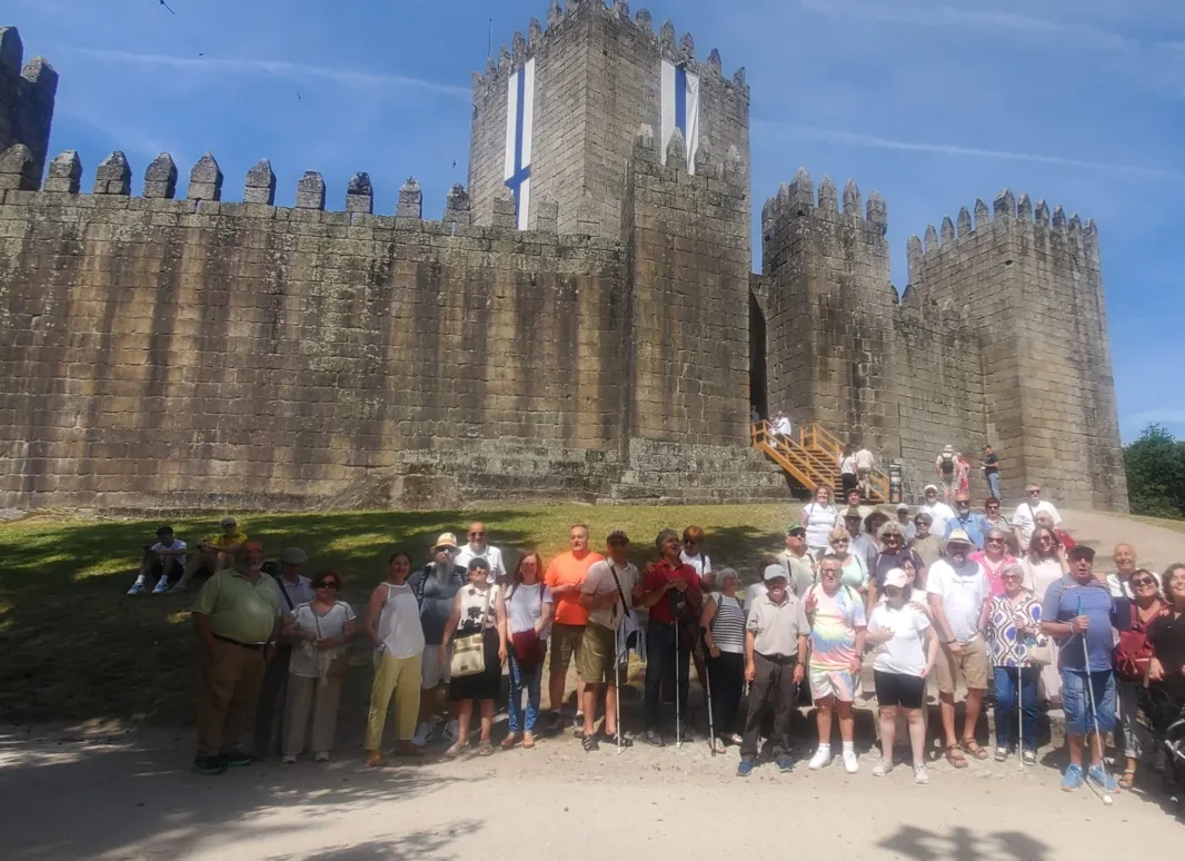 Grupo de participantes de la excursión de SUPO Vigo-Pontevedra posando frente a una fortaleza medieval durante su visita al norte de Portugal.