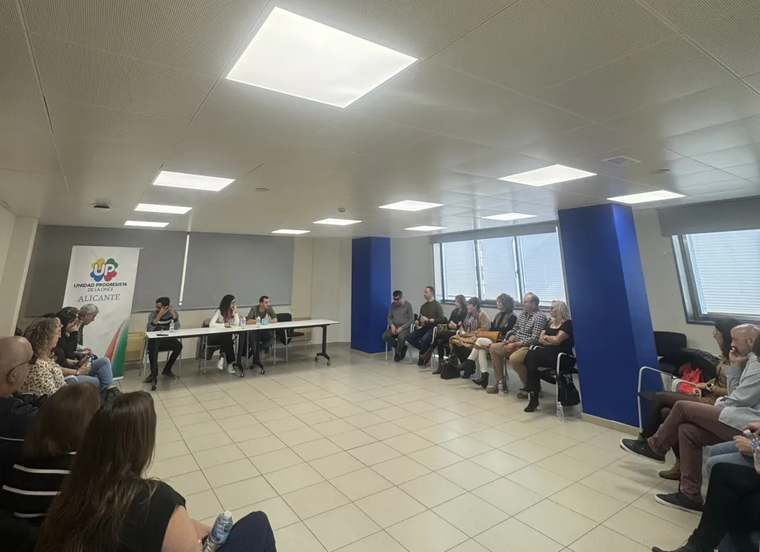 Se muestra un sillas formando un semicírculo con los miembros de la ejecutiva y los moderadores en una mesa