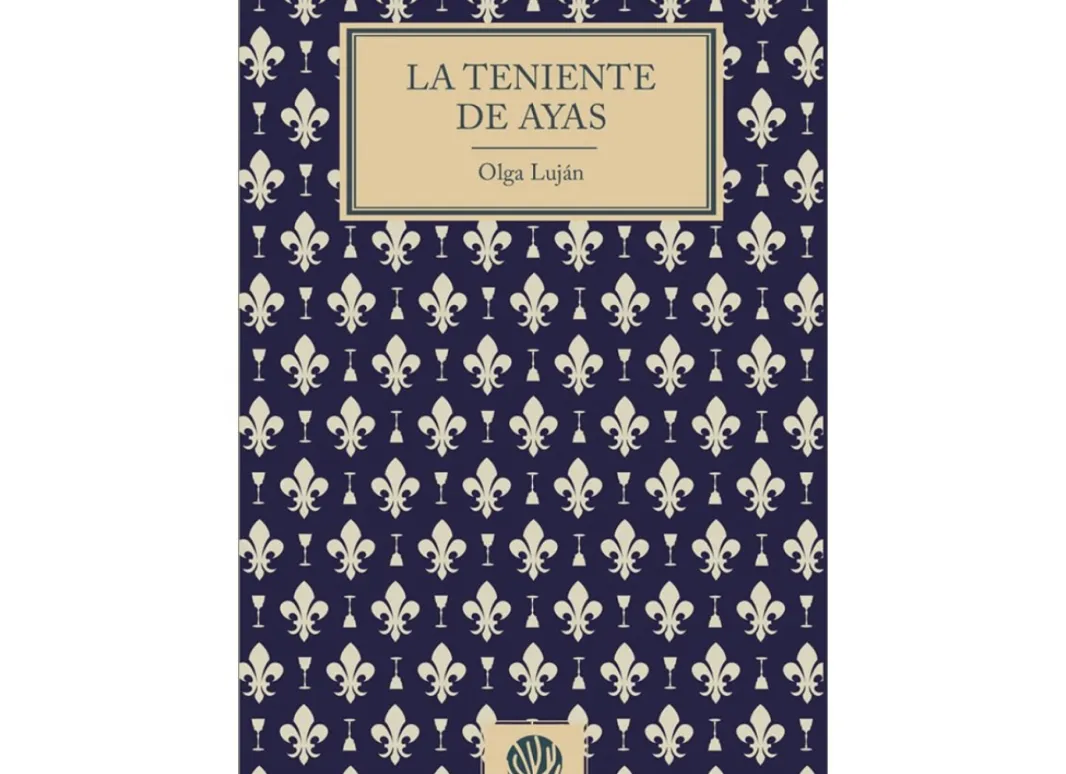 Imagen de la portada de la obra. La imagen muestra la cubiertas original de la obra, caracterizada por un estampado clásico de flores de lis blancas y copas sobre un fondo azul índigo. En la parte central, un recuadro sobrio de color crema enmarca el título La teniente de Ayas y el nombre de la autora. 