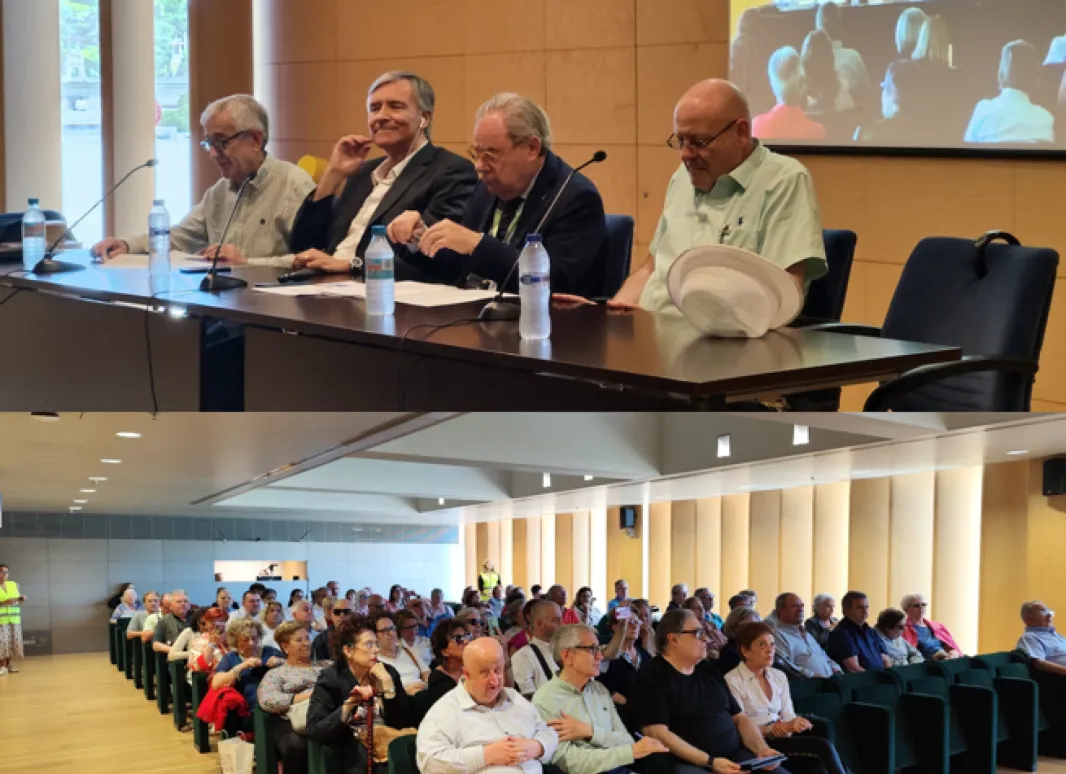 Foto de la conferencia con la mesa de ponentes y el público.