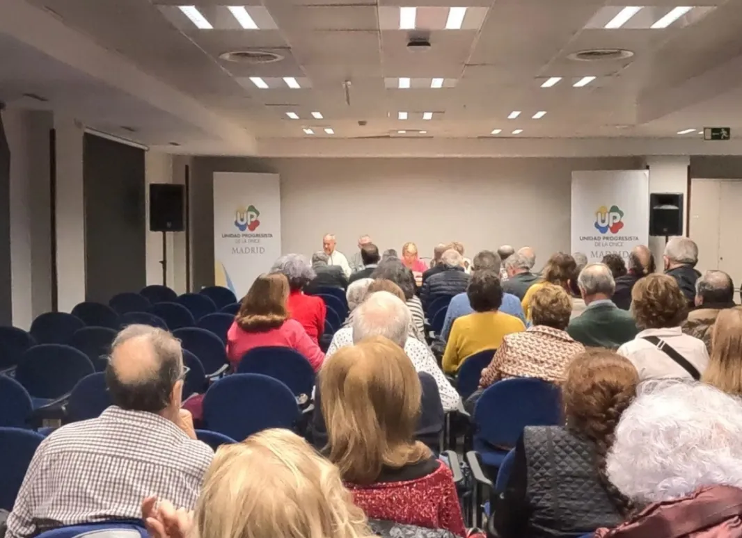 Foto desde el fondo de la sala donde se ha celebrado la Asamblea, con un lleno de socios y socias. 