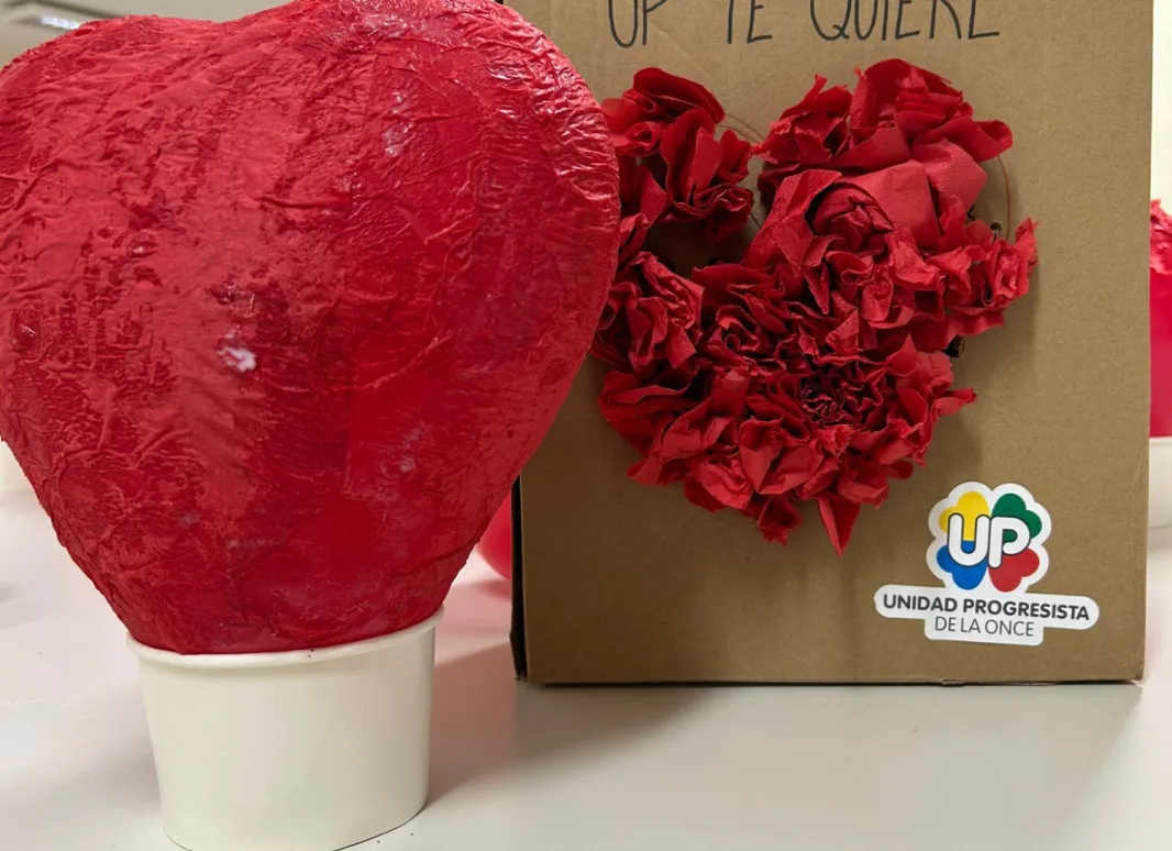 Globo con forma de corazón , cubierto cuidadosamente con capas de servilletas rojas pegadas con cola, formando una superficie firme y texturizada que simboliza el amor y la inclusión.