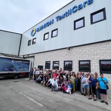 IMAGEN DEL GRUPO DE UP GIJÓN A LA ENTRADA DE ILUNION TEXTIL CARE CON SUS RESPONSABLES