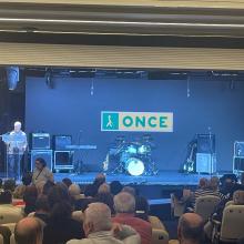 Foto del escenario del salón de actos lleno de instrumento y un patio de butacas con el aforo completo 