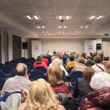 Foto desde el fondo de la sala donde se ha celebrado la Asamblea, con un lleno de socios y socias. 