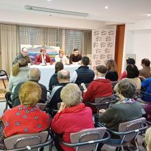 FOTO DE LA CELEBRACION DE LA ASAMBLEA CON LOS ASISTENTES SENTADOS ESCUCHANDO A LA SECRETARIA GENERAL DE LA AGRUPACIÓN