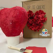 Globo con forma de corazón , cubierto cuidadosamente con capas de servilletas rojas pegadas con cola, formando una superficie firme y texturizada que simboliza el amor y la inclusión.